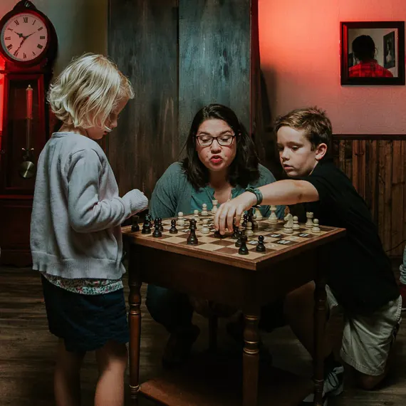 A family playing chess in the Mystery Mansion room